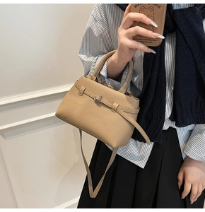 Detail view of beige pebbled leather bucket bag with top handle and strap in real use
