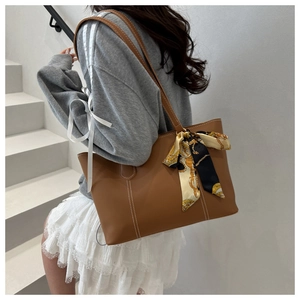 Brown leather tote bag with white stitching detail and a decorative printed silk scarf