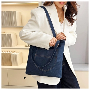 Detail of deep blue denim tote bag with curved pocket and vintage fabric texture
