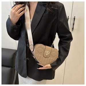 Detail of khaki heart-shaped crossbody bag with quilted texture and golden buckle