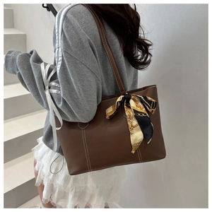 Detail of dark brown tote bag with contrast stitching and decorative silk scarf
