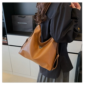 Detail view of large caramel brown leather tote bag with metallic triangle logo
