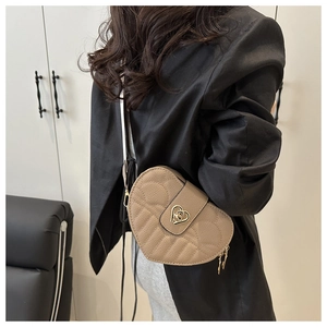 Detail of heart-shaped crossbody bag featuring quilted stitching and golden metal clasp