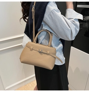Detail of khaki pebbled leather bucket bag with top handle and metal buckle decoration