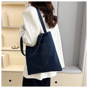 Detail view of a vintage dark blue denim tote bag with contrast stitching on white blazer