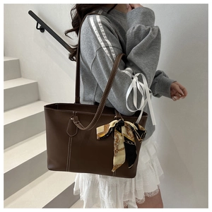 Brown leather tote bag with white contrast stitching and a vintage patterned silk scarf