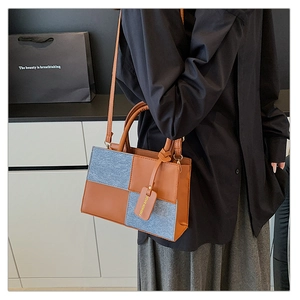Detail showing the mixed materials of the vintage-style handbag with hanging tag decoration