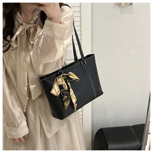 Detail of black tote bag featuring contrast white stitching and a floral silk scarf handle
