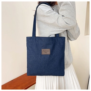 Detail shot of vintage blue denim tote bag featuring fashion bag leather patch on a model