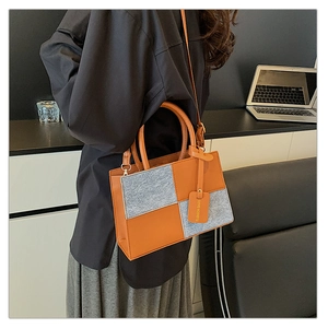 Detail of trendy color-block contrast tote bag with grey felt and orange leather patterns