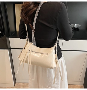 Bolso de hombro blanco crema con elegantes borlas de cuero en un ambiente minimalista