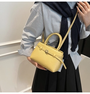 Detail of yellow pebbled leather bucket bag with top handle and metal pin buckle