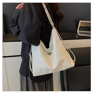 Detail of white leather tote bag with metal triangle logo and fine pebble grain texture