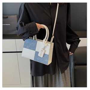 Detail of color-block leather handbag featuring blue and white stitching with fashion tag