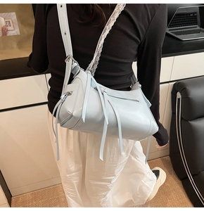 Detalle del bolso bandolera de cuero azul claro con borlas largas y correa de encaje