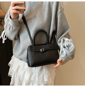 Detail of black lychee texture leather handbag with silver buckle and round handle