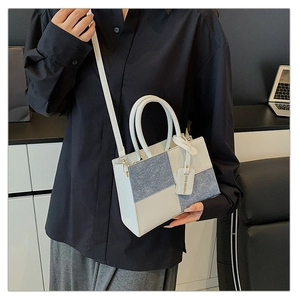 Detail of white leather and light blue denim patchwork handbag with a fashion charm