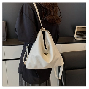 Detail of white lychee grain leather tote bag with metal logo on a model's shoulder