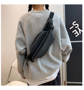 Détail de la bandoulière réglable et du logo sport sur le sac bandoulière gris foncé