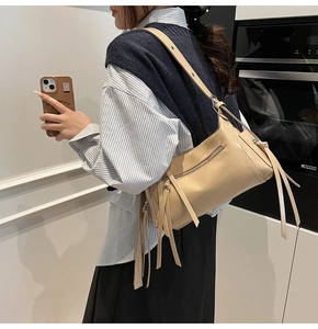 Vista detallada del bolso de hombro beige en ecocuero con largos flecos bohemios