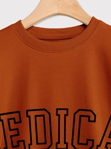 Detail of rust brown crew neck sweatshirt featuring ribbed collar and black EDICA print