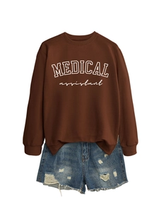 Close-up of Medical Assistant print on brown sweatshirt with frayed denim shorts