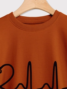 Close-up of caramel sweatshirt neckline with ribbed collar and black EKG wave print