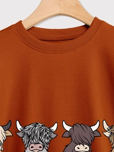 Detail of caramel crewneck sweatshirt with ribbed collar and Highland cow prints