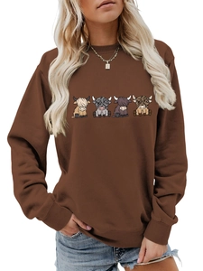 Detail of loose-fit brown sweatshirt with cartoon highland cow prints and ribbed cuffs