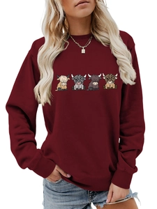 Close-up of ribbed cuffs and detailed cartoon highland cow prints on a burgundy sweatshirt