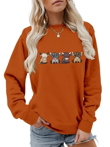 Detail of orange crewneck sweatshirt featuring four cartoon highland cow prints and ribbed cuffs