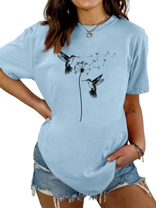 Detail eines hellblauen T-Shirts mit Löwenzahn- und Kolibri-Print und Jeans-Shorts