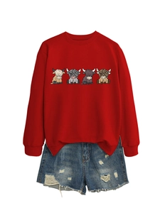 Flat lay of red crewneck sweatshirt featuring four cartoon cows with denim shorts