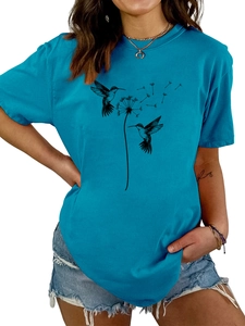 Detail eines blauen T-Shirts mit schwarzem Kolibri- und Löwenzahn-Print auf dem Stoff