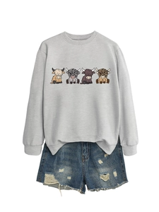 Flat lay of grey crewneck sweatshirt with highland cattle print and ripped denim shorts