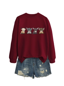 Detail of burgundy sweatshirt featuring colorful highland cow prints and ripped denim shorts