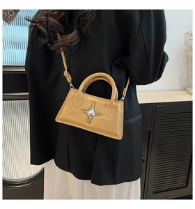 Détail d'un sac bandoulière jaune moutarde structuré avec emblème étoile sur un mannequin