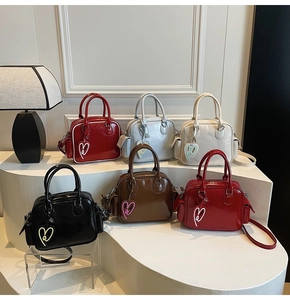 Detail view of glossy leather Boston bags in six colors with heart charms on display