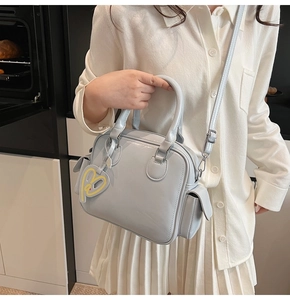 Close-up of a light blue Boston tote bag with a heart charm and detachable shoulder strap