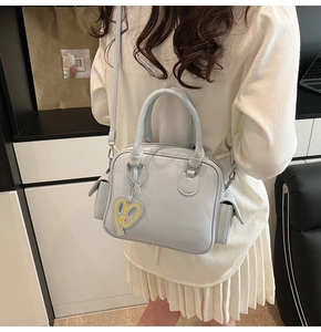 Detail of light blue glossy Boston tote with side pockets and yellow heart charm