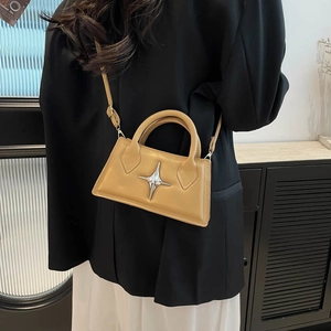 Sac à main en cuir kaki avec étoile métallique porté par un mannequin en costume