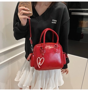 Detail of red patent leather Boston tote bag with a white heart charm and dual handles