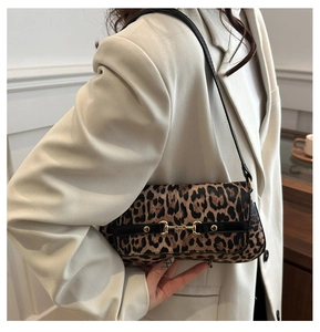 Détail du sac léopard sous le bras avec mors doré et bandoulière en cuir noir