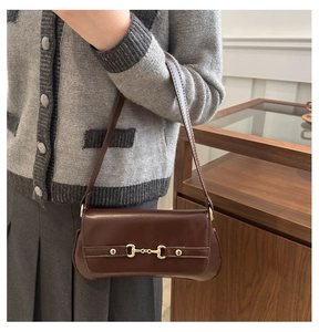 Détail d'un sac sous le bras marron foncé rétro avec une boucle mors en métal doré chic