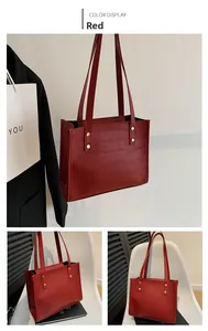Detail of dark red tote bag showing crocodile texture embossing and gold metal rivets
