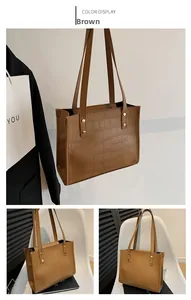 Detail view of brown faux leather tote bag with crocodile embossing and golden rivets