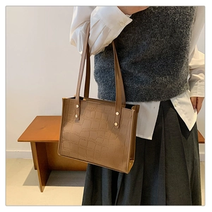 Detail of vintage brown crocodile embossed tote bag with gold rivets and leather texture