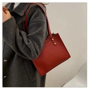 Detail shot of vintage burgundy tote bag with embossed crocodile texture and gold rivets