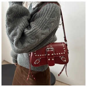 Detail of dark red vintage punk crossbody bag with silver studs on a grey sweater