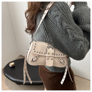 Close-up of cream Y2K motorcycle shoulder bag with silver rivets and adjustable strap